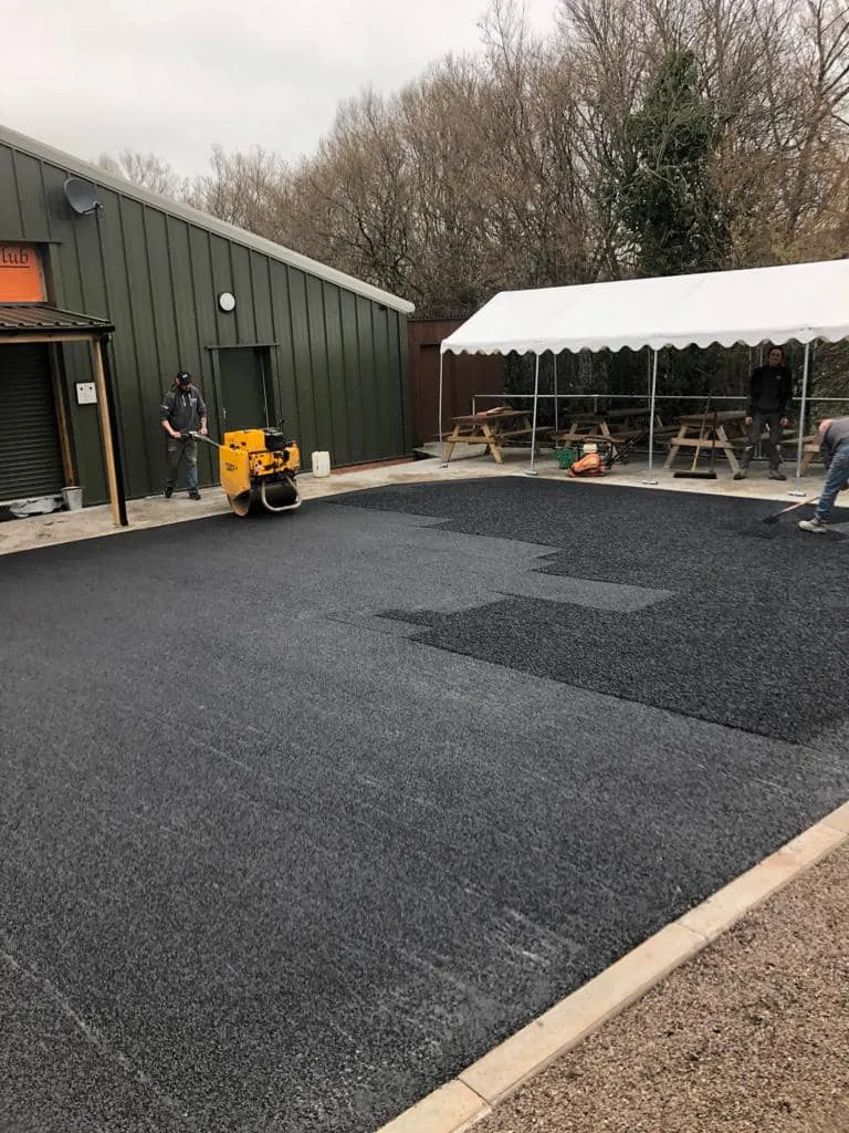 a man is working on a tarmac in front of a building